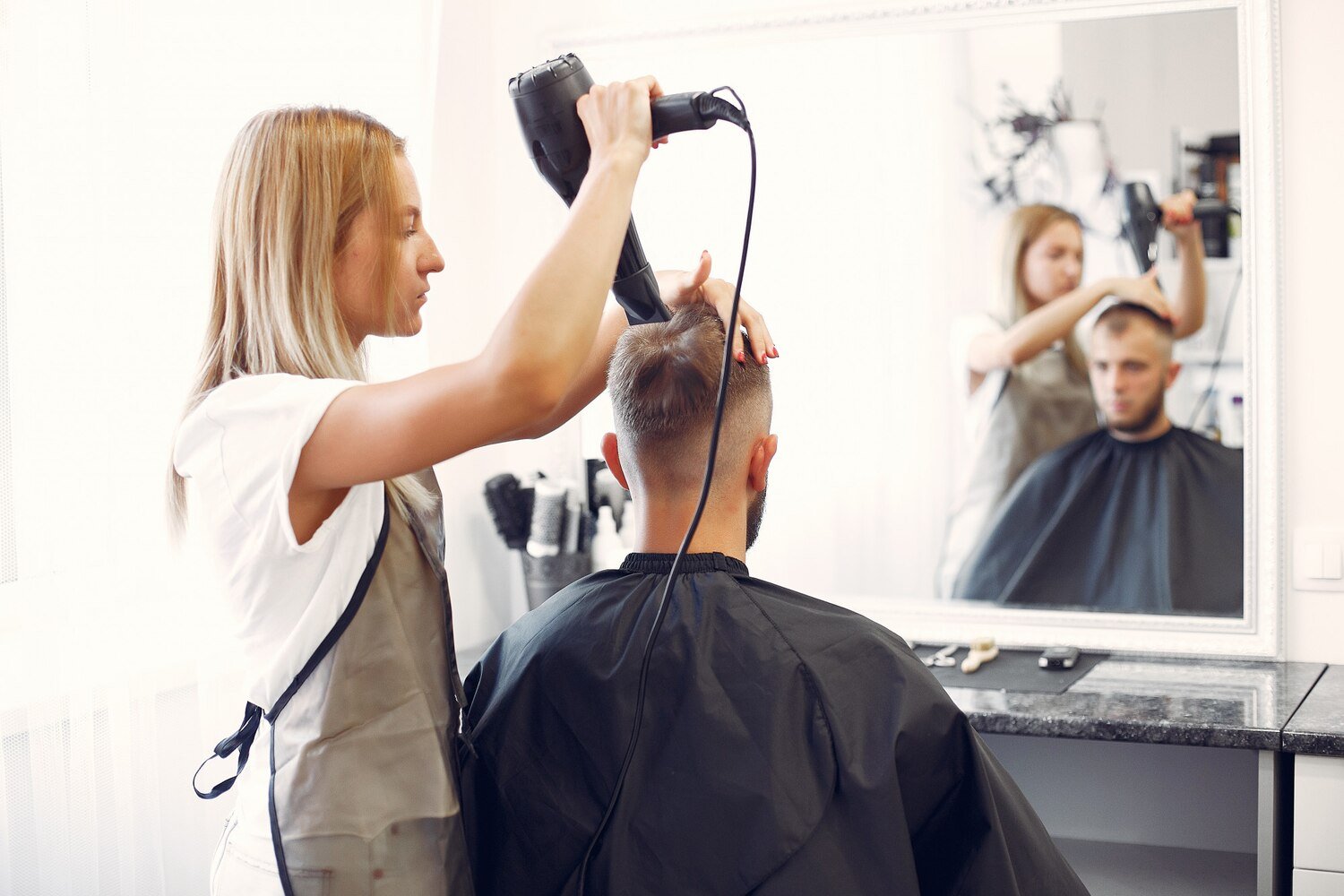Stilistă care aranjează părul unui client